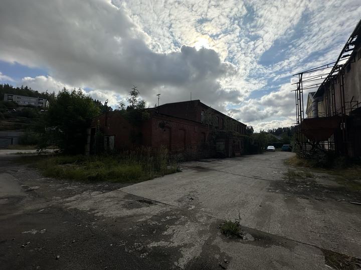 Open yard between brick works buildings under a broken sky