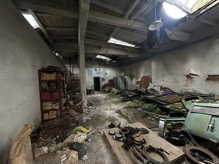 Workshop bay with exposed brickwork, shelving and scattered plant parts