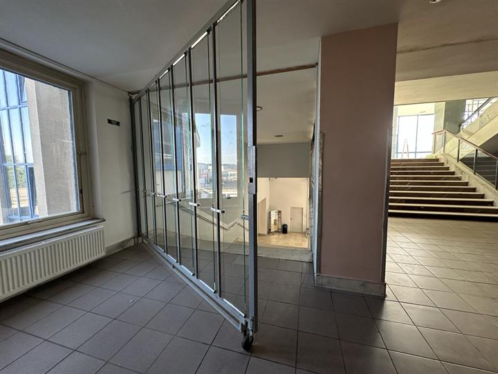 Office floor divided by a glazed partition, with a staircase beyond