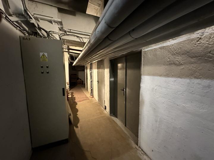 Service corridor with a switchgear cabinet and overhead pipework