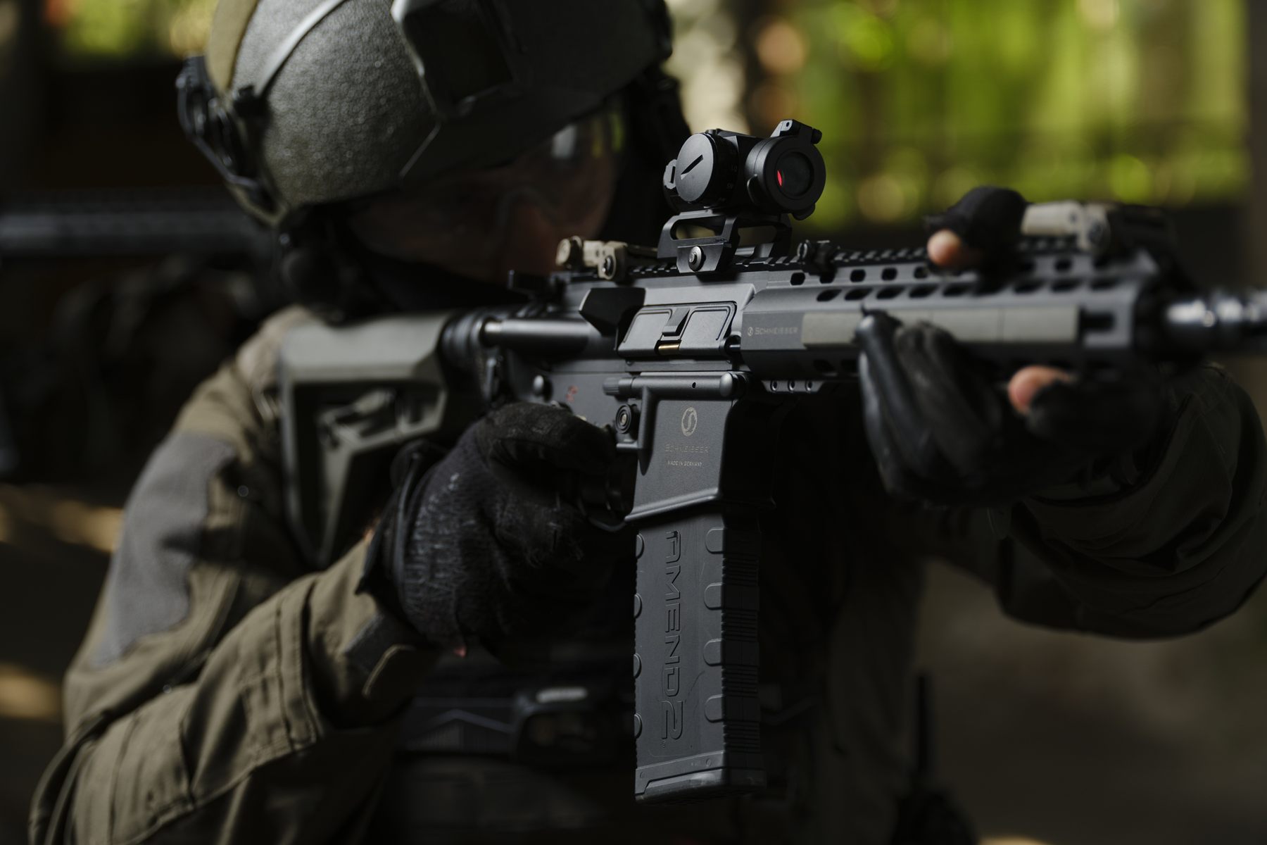 Operator aiming a carbine with a red-dot sight