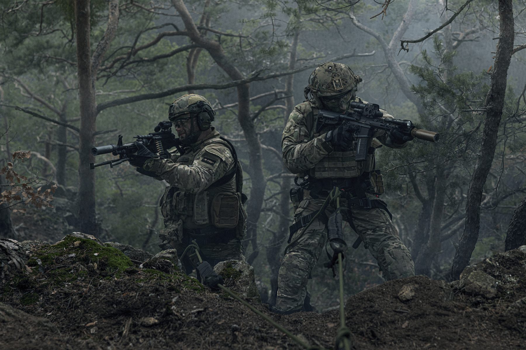 Two soldiers advancing through a smoky forest with carbines raised